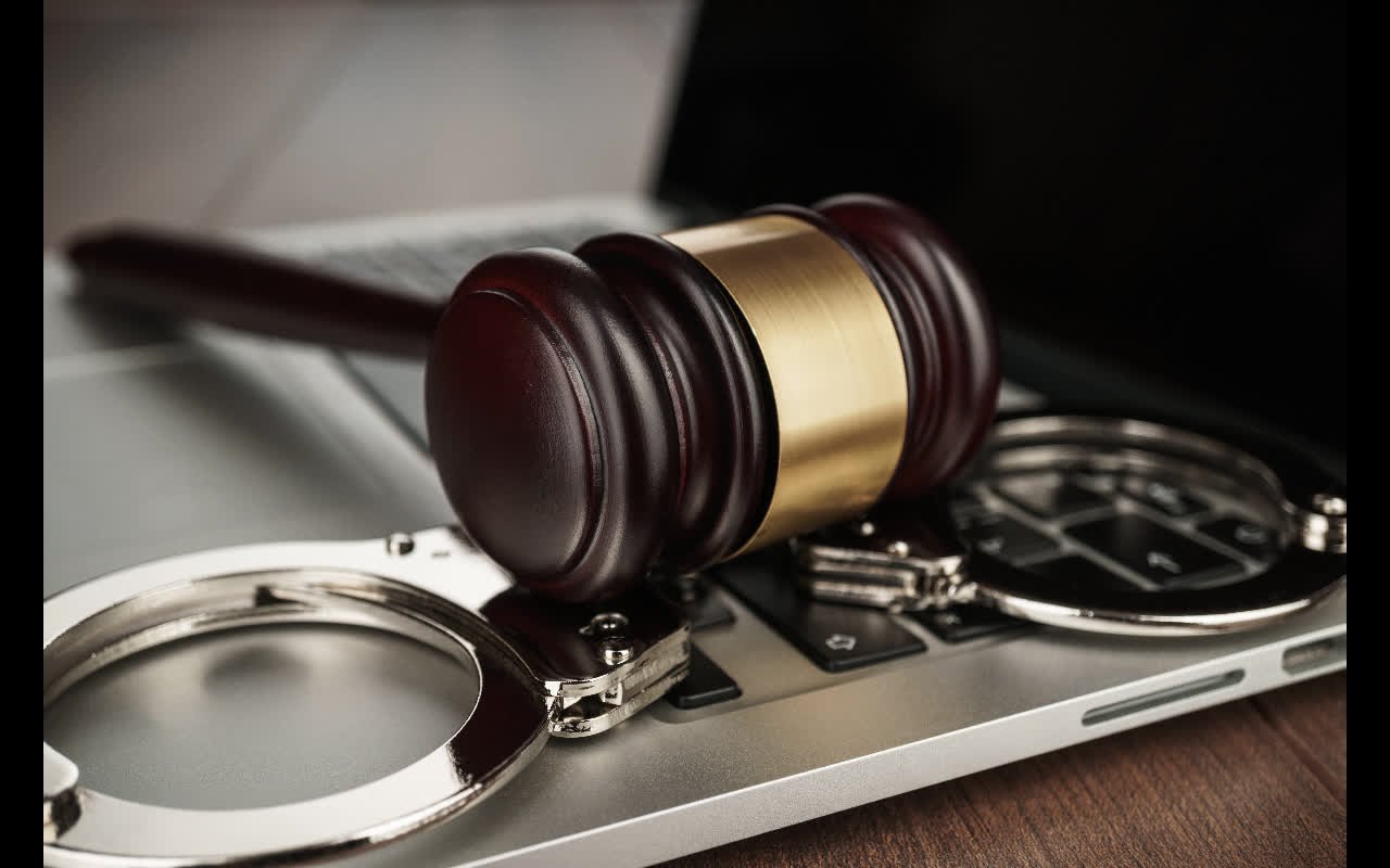 Handcuffs and a judge’s gavel on a laptop