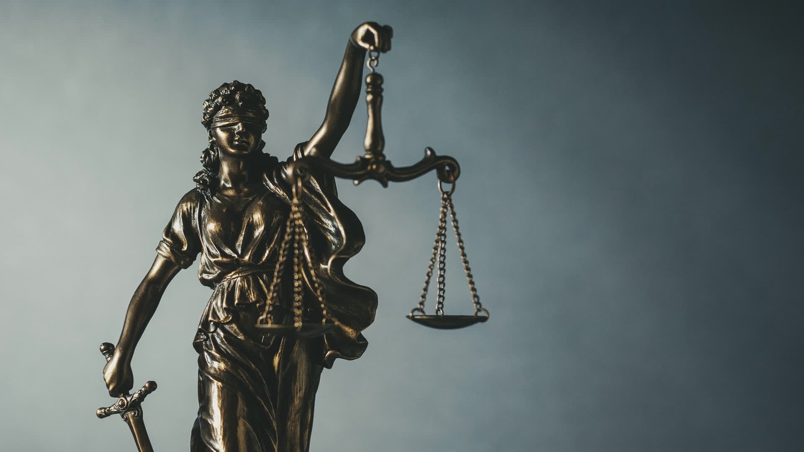 Brass statue of Lady Justice holding scales and a sword
