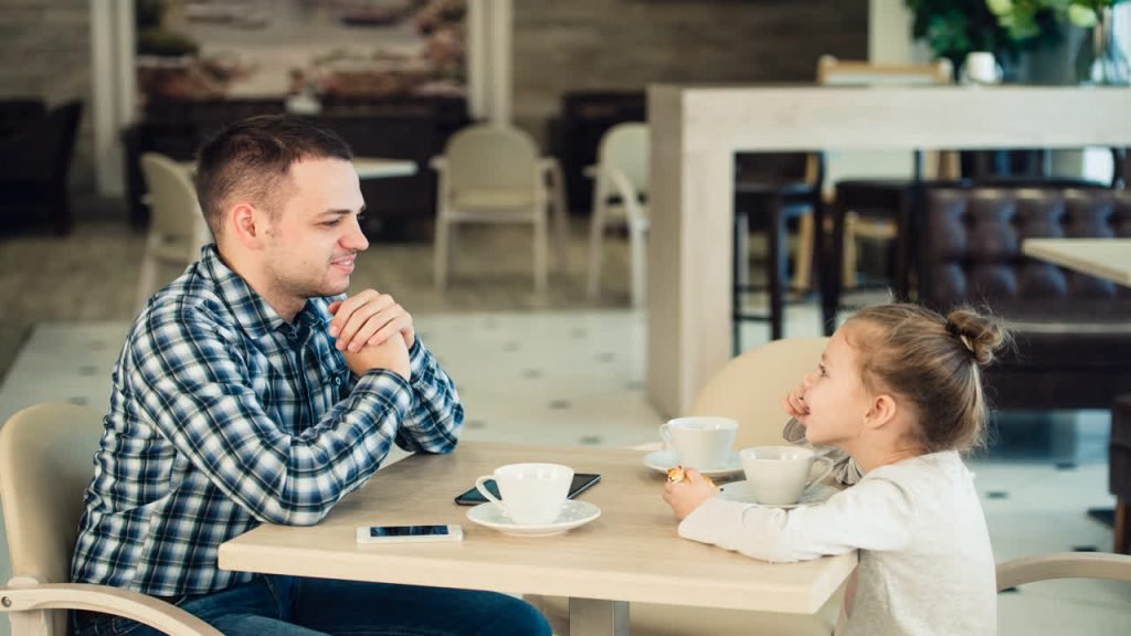 A father and daughter at a café table