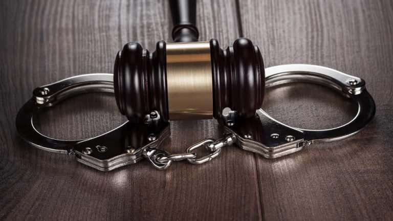 Handcuffs beside a judge’s gavel